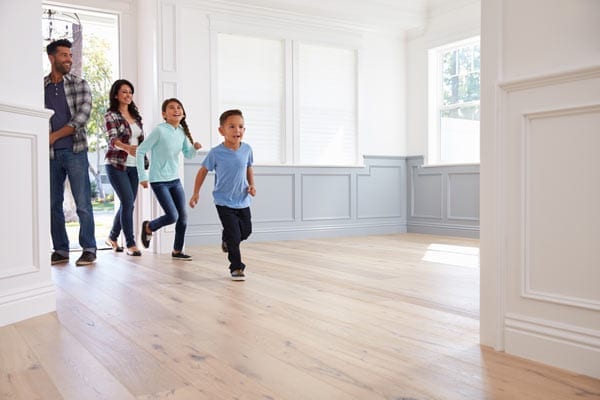 Happy family entering their hardwood floor home